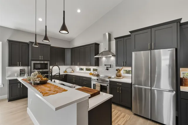 a kitchen with stainless steel appliances a stove a refrigerator a sink and a refrigerator