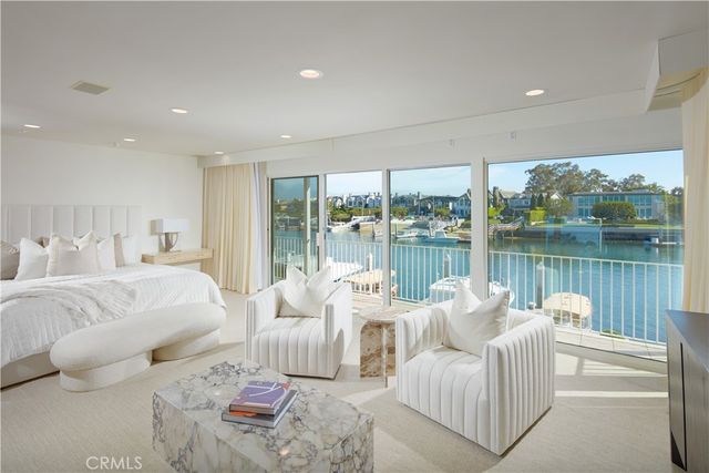 a living room with furniture large windows and wooden floor
