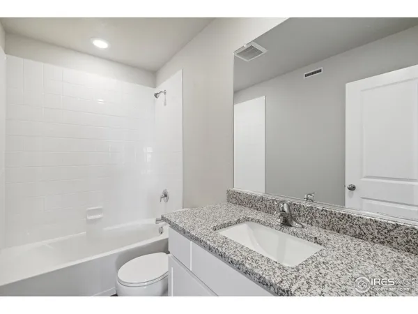 a bathroom with a granite countertop sink a toilet and bathtub