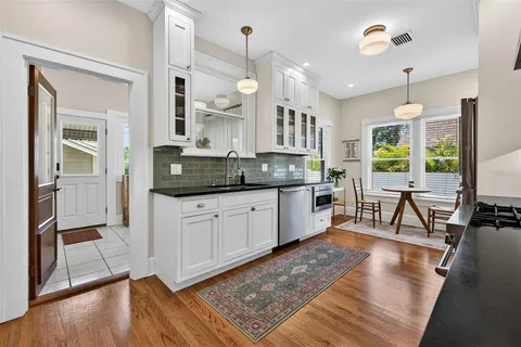a large kitchen with granite countertop a stove a sink and a wooden floor