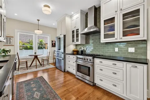 a kitchen with stainless steel appliances granite countertop a stove a sink and white cabinets