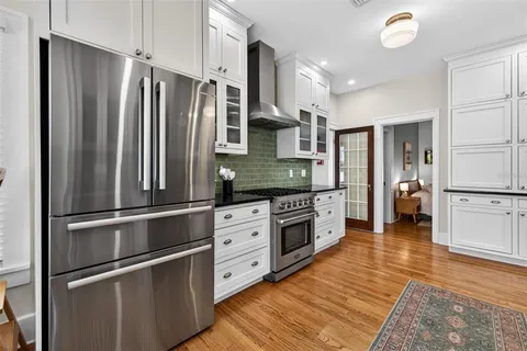 a kitchen with granite countertop stainless steel appliances a refrigerator cabinets and wooden floor