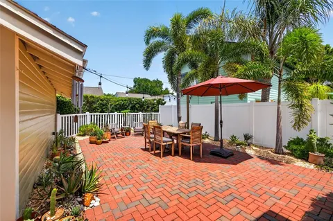 a view of a patio with a table and chairs under an umbrella with potted plants