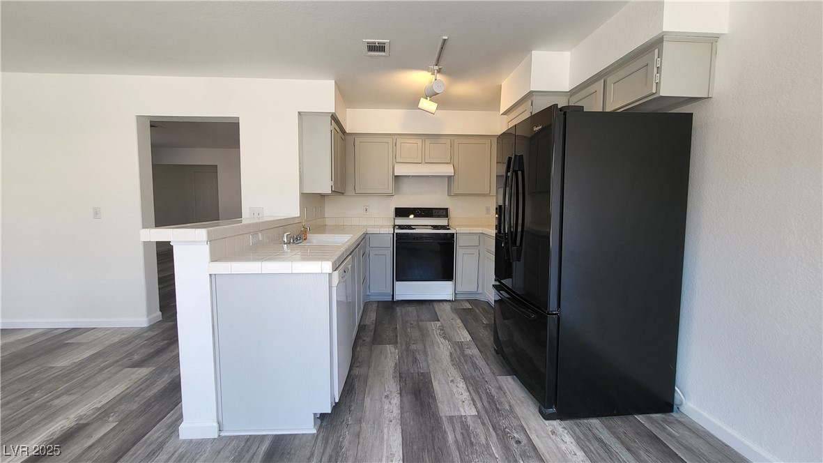 306 Lander Drive Henderson, NV 89074 - Photo 6 of 30 Kitchen with tile countertops, gray cabinets, white appliances, dark wood-style flooring, and under cabinet range hood