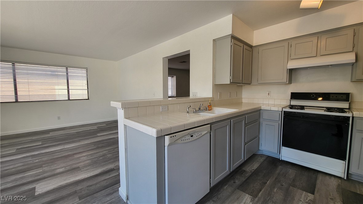 306 Lander Drive Henderson, NV 89074 - Photo 8 of 30 Kitchen with gray cabinets, gas range oven, dishwasher, dark wood-type flooring, and under cabinet range hood