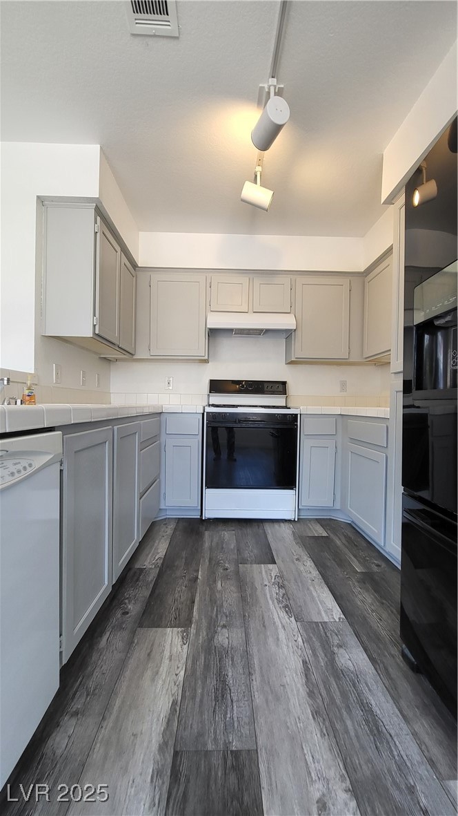 306 Lander Drive Henderson, NV 89074 - Photo 9 of 30 Kitchen featuring gray cabinets, black range, tile counters, dishwasher, and dark wood-style flooring