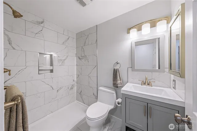 a bathroom with a toilet sink vanity and mirror