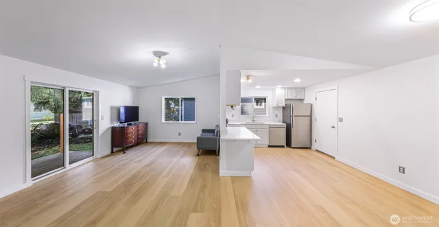 a large living room with stainless steel appliances kitchen view and wooden floor
