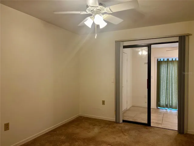 an empty room with a chandelier fan and windows