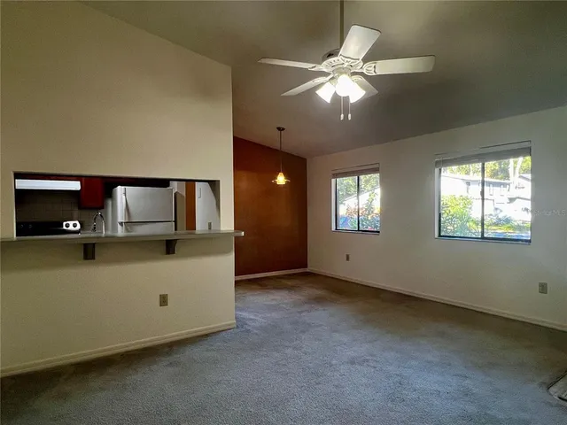 an empty room with windows and ceiling fan