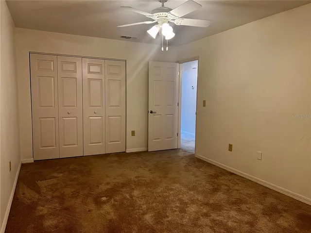 an empty room with closet and a chandelier fan