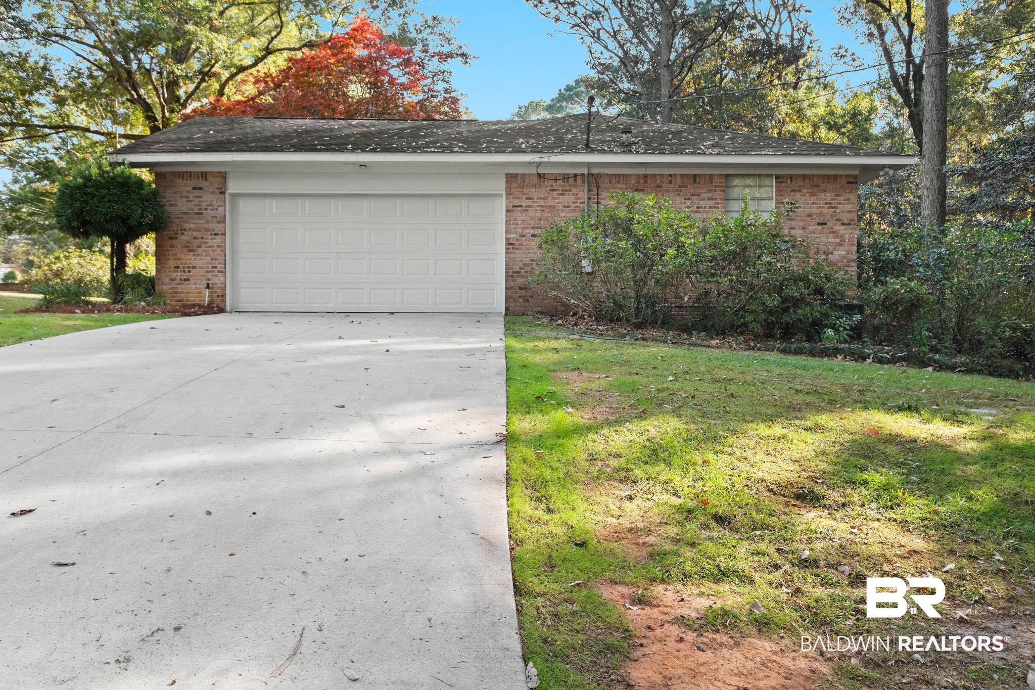 752 Evergreen Street Fairhope, AL 36532 - Photo 77 of 100 View of front of property featuring brick siding, driveway, a front lawn, and an attached garage