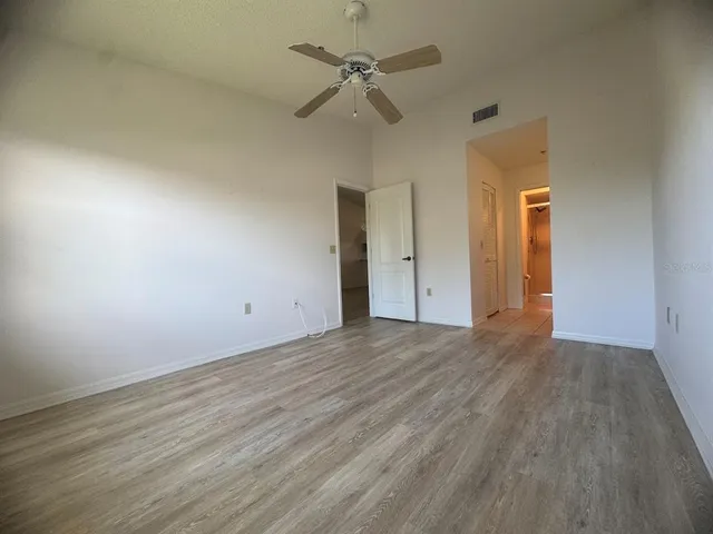 an empty room with a ceiling fan and wooden floor