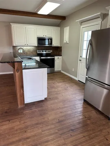 a kitchen with granite countertop a refrigerator and a stove top oven