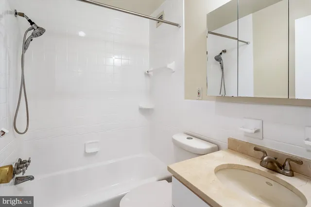 a bathroom with a granite countertop sink a toilet and shower
