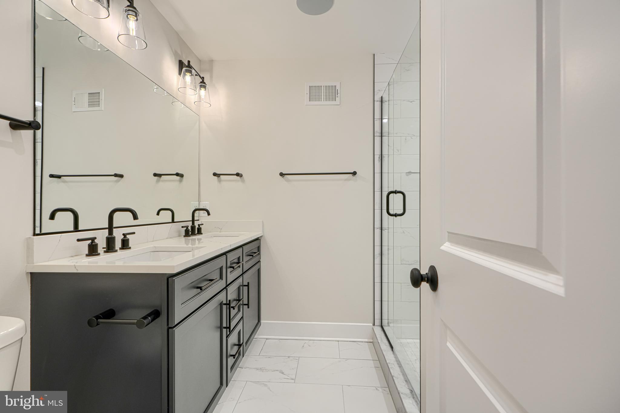 1427 Patapsco Street Baltimore, MD 21230 - Photo 27 of 34 a bathroom with a double vanity sink a mirror and shower