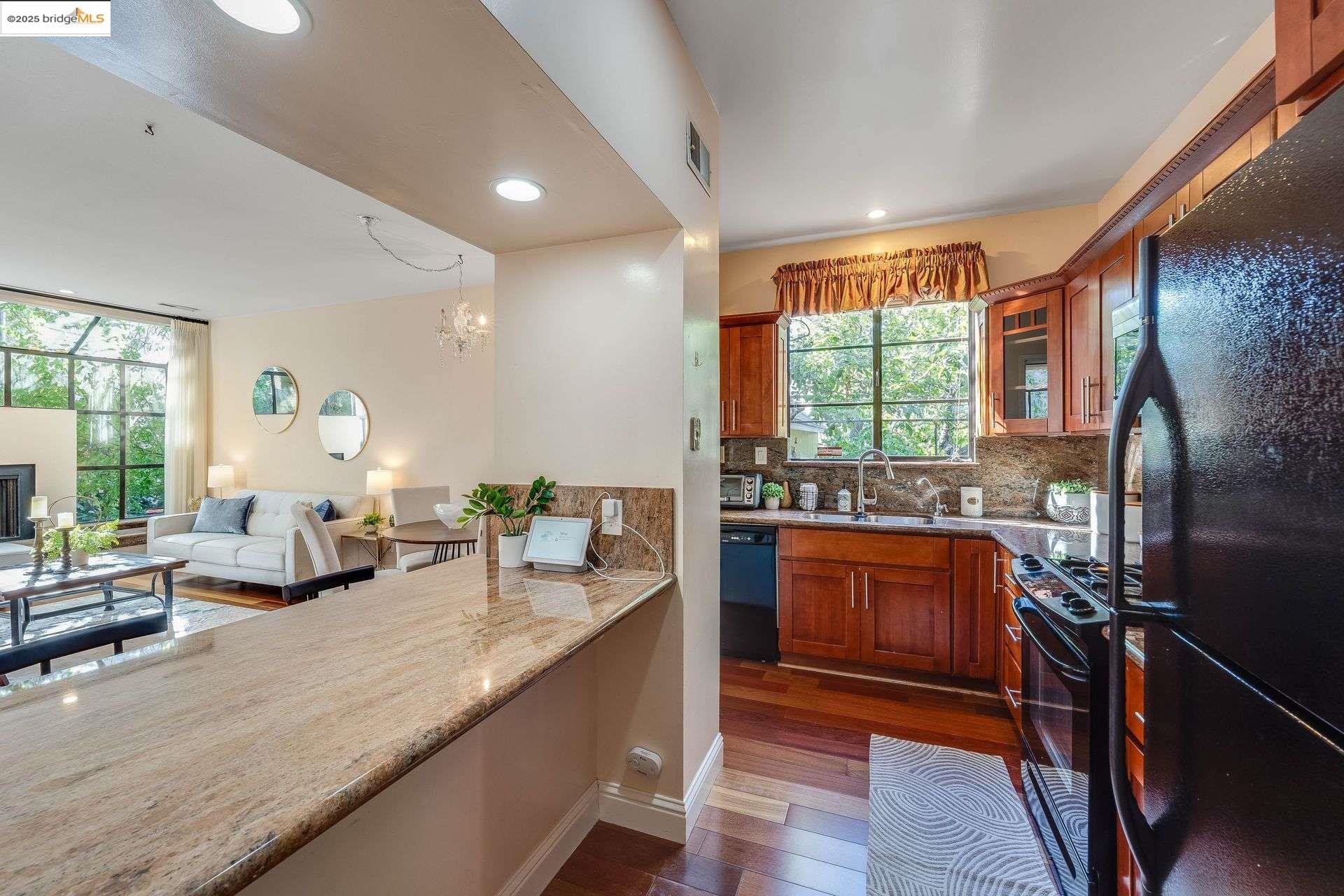 2316 Blake Street, Unit D Berkeley, CA 94704 - Photo 31 of 31 Kitchen with black appliances, dark wood finished floors, decorative backsplash, brown cabinets, and open floor plan