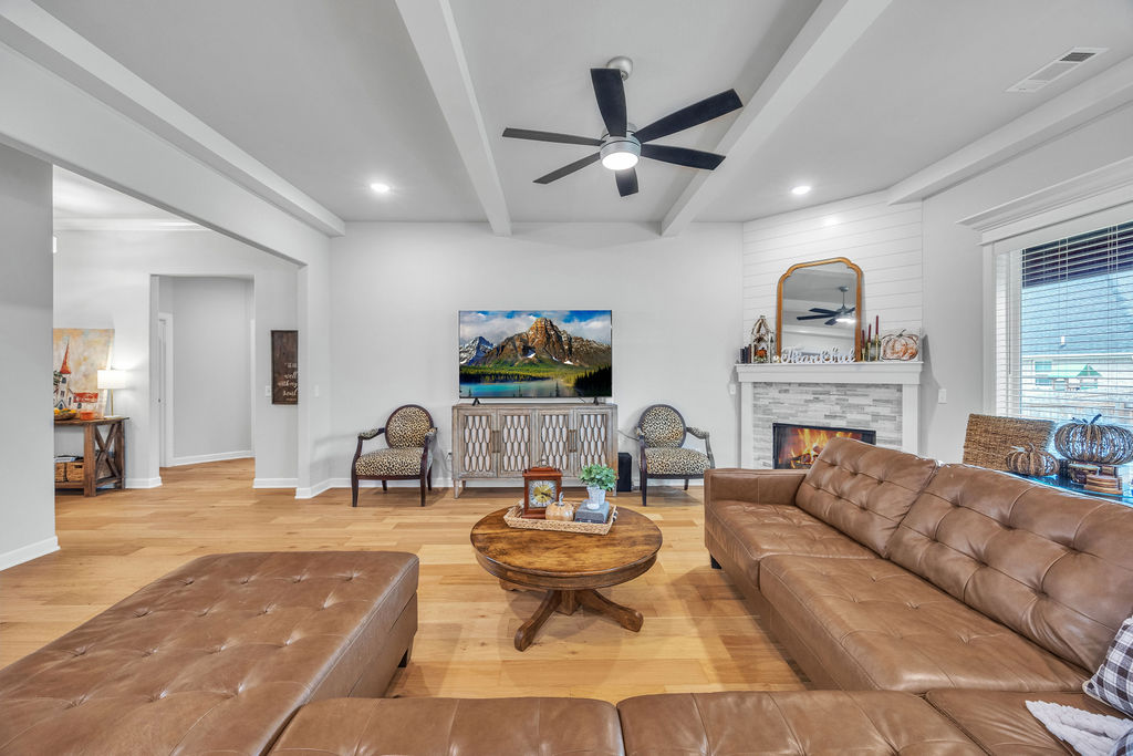 418 Casella Street Springdale, AR 72762 - Photo 8 of 34 Vaulted ceiling with exposed beams, wood-finish flooring, built-in electric fireplace with tile surround, shiplap accent wall, and recessed lighting