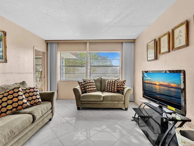 a living room with furniture a flat screen tv and a floor to ceiling window