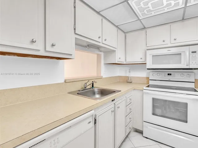 a kitchen with white cabinets and white appliances