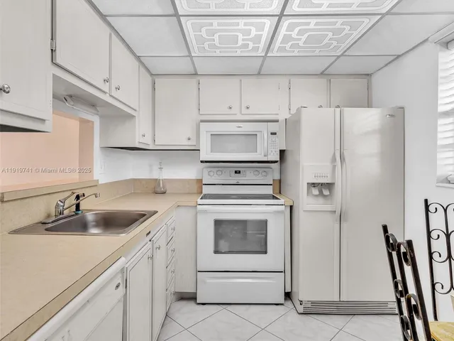 a kitchen with a sink a refrigerator and cabinets