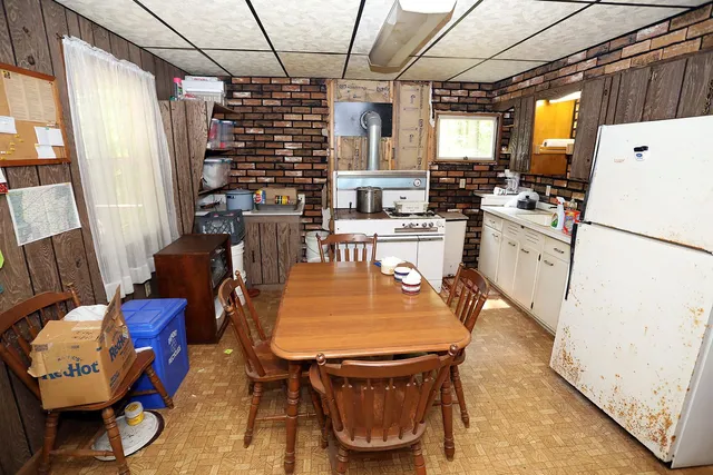 a dining room with furniture a kitchen wooden floor and a chandelier