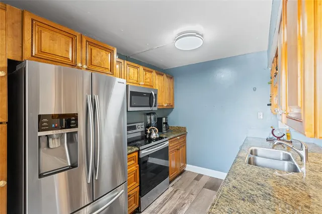 a kitchen with stainless steel appliances granite countertop a refrigerator a sink a stove and island