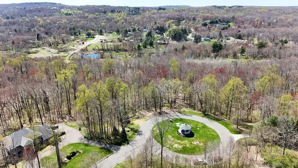 an aerial view of residential house with outdoor space and trees all around