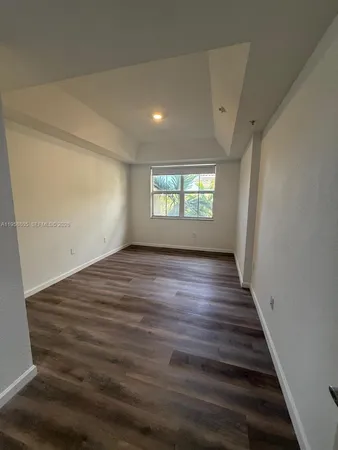 a view of an empty room with wooden floor and window