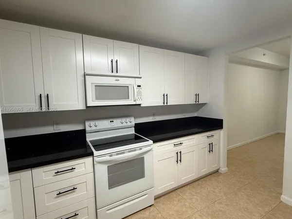 a kitchen with granite countertop white cabinets and white appliances