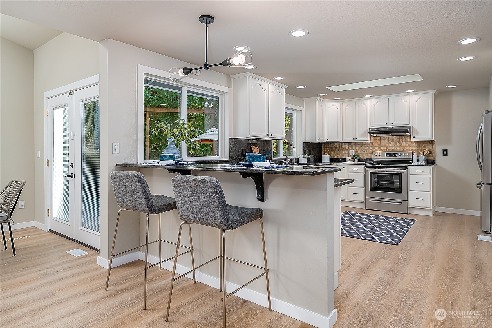 24121 6th Place West Bothell, WA 98021 - Photo 8 of 32 a kitchen with stainless steel appliances granite countertop a stove top oven a sink dishwasher a dining table and chairs with wooden floor