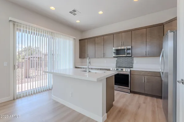 a kitchen with kitchen island a sink stainless steel appliances and cabinets