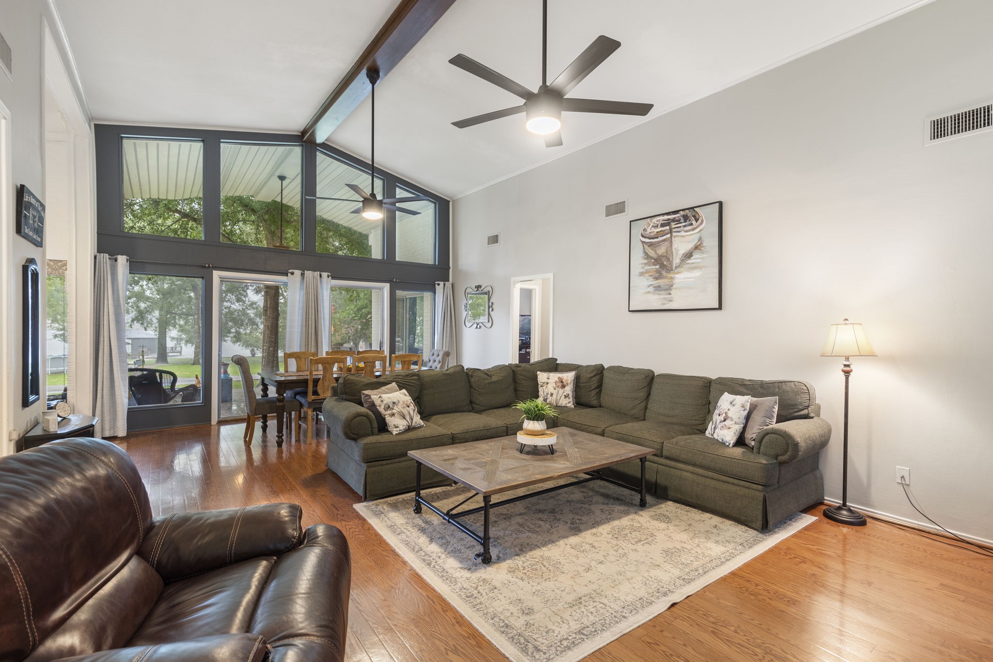 245 Lakeland Road Huntsville, TX 77320 - Photo 8 of 49 Experience breathtaking lake views through the expansive windows of this home, featuring tall ceilings with an elegant beam, and two ceiling fans that enhance the airy and open atmosphere