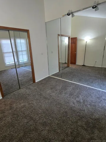 a view of an empty room with wooden floor and a mirror