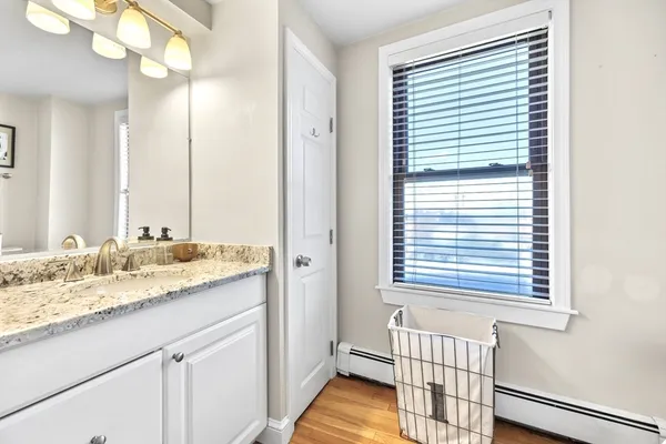 a bathroom with a granite countertop sink and a window