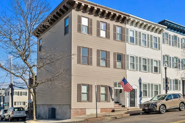 a front view of a building with lot of cars and trees