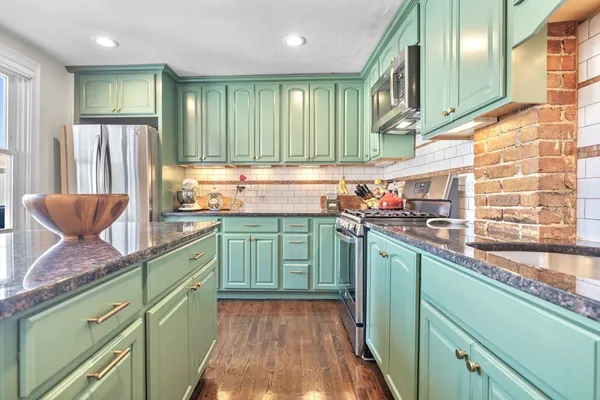 a kitchen with stainless steel appliances granite countertop a sink a microwave cabinets and a wooden floor