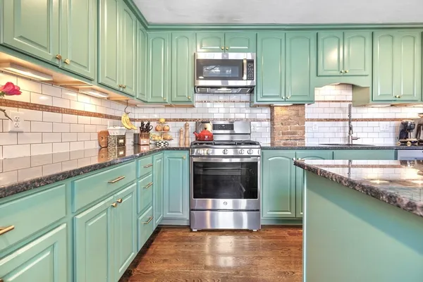a kitchen with stainless steel appliances granite countertop a sink a stove and cabinets
