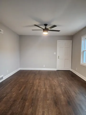 a view of an empty room with wooden floor and a window