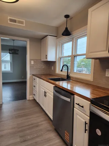 a kitchen with stainless steel appliances granite countertop a sink a stove cabinets and a window