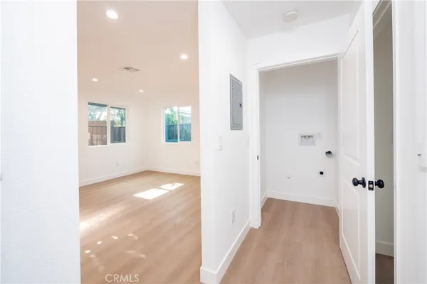 a view of a hallway with wooden floor and a bathroom