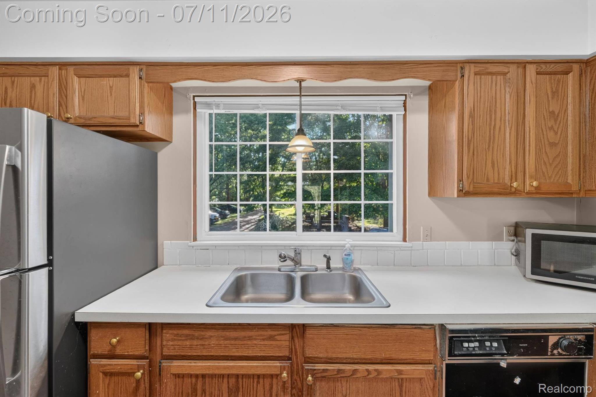 4430 North Center Road Flint, MI 48506 - Photo 13 of 49 Kitchen featuring a double stainless steel sink, a window with grid inserts, wood-finish cabinetry, and white countertops