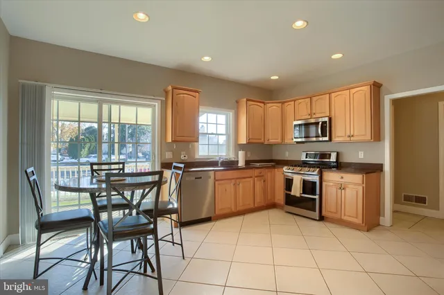 a kitchen with stainless steel appliances granite countertop a stove a sink a dining table and chairs
