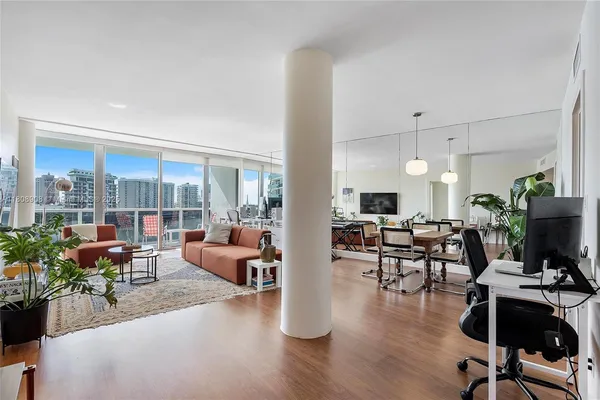 a living room with furniture potted plant floor to ceiling window and potted plant