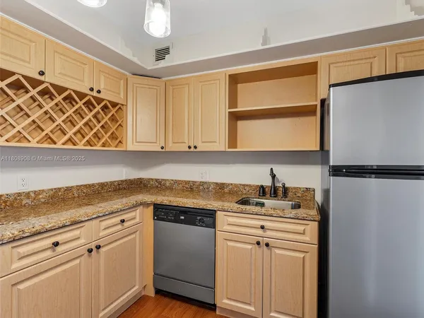 a kitchen with stainless steel appliances granite countertop a sink a stove a refrigerator with white cabinets and wooden floor
