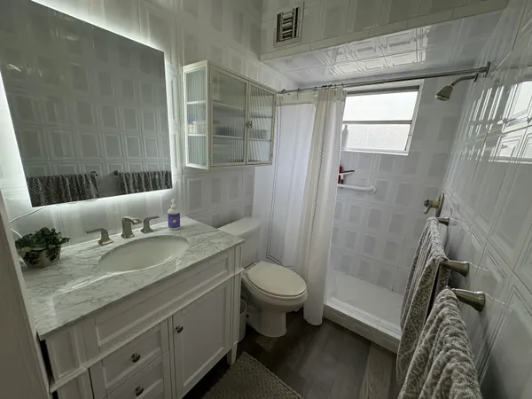 a bathroom with a granite countertop sink toilet and shower