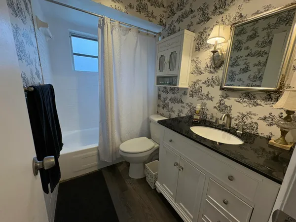 a bathroom with a granite countertop sink toilet and shower