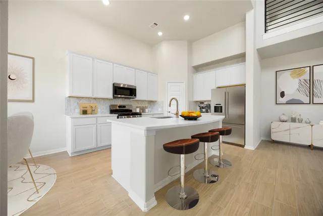 a kitchen with stainless steel appliances a stove a sink a microwave a refrigerator and cabinets