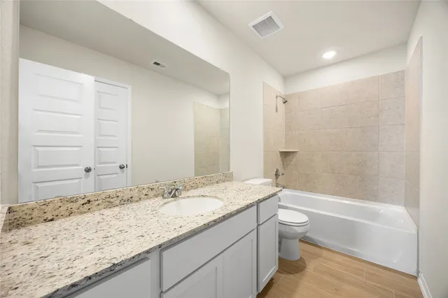 a bathroom with a granite countertop sink a toilet and bathtub