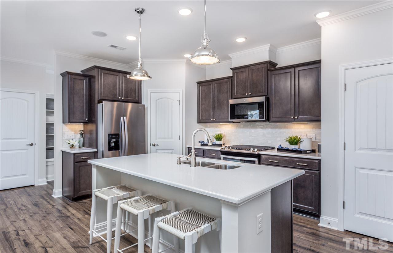 1720 Highpoint Street, Unit HV 264 Wake Forest, NC 27587 - Photo 8 of 20 a kitchen with kitchen island a sink stainless steel appliances and refrigerator